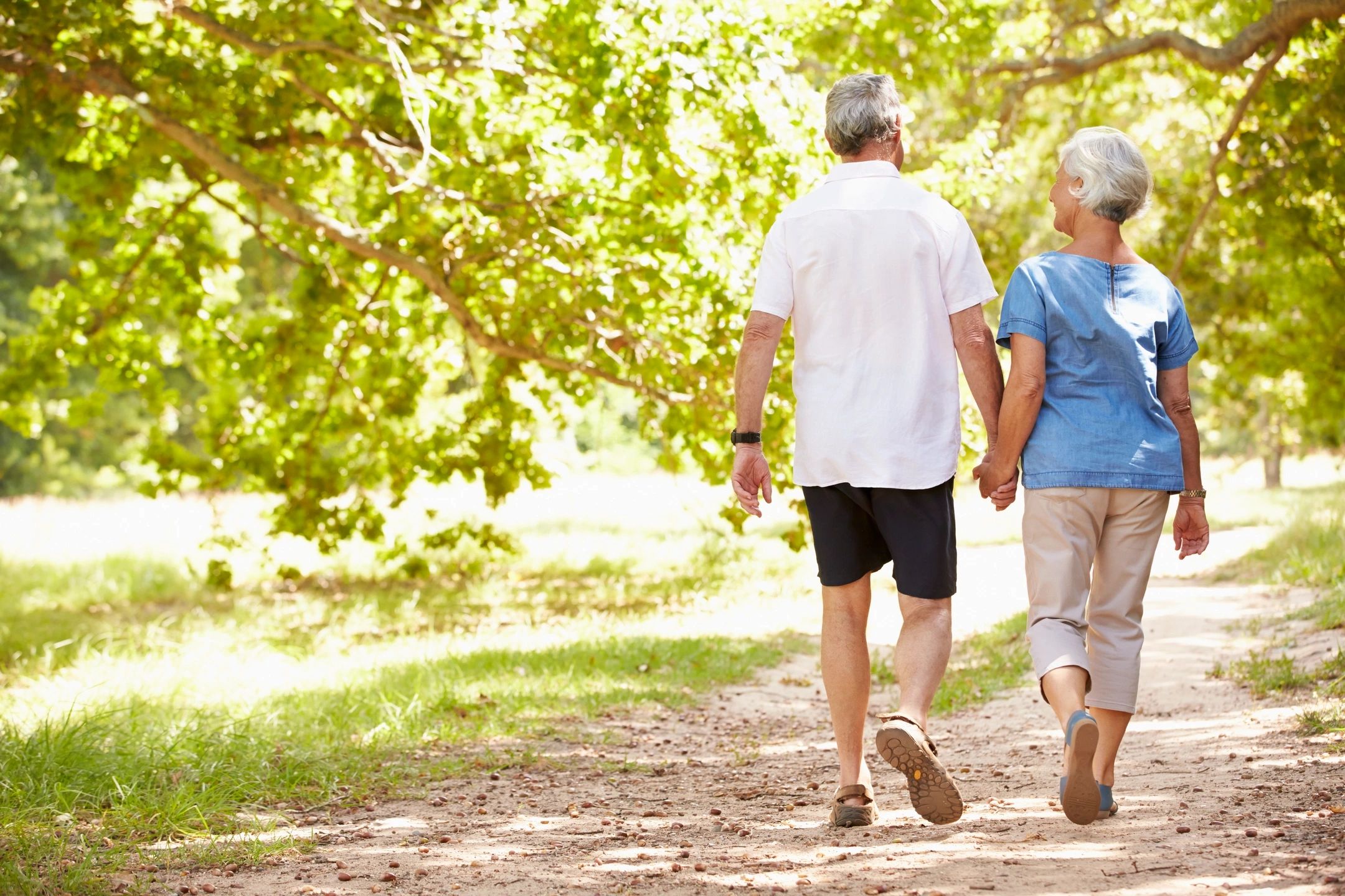 Elderly couple walking down a dirt path.